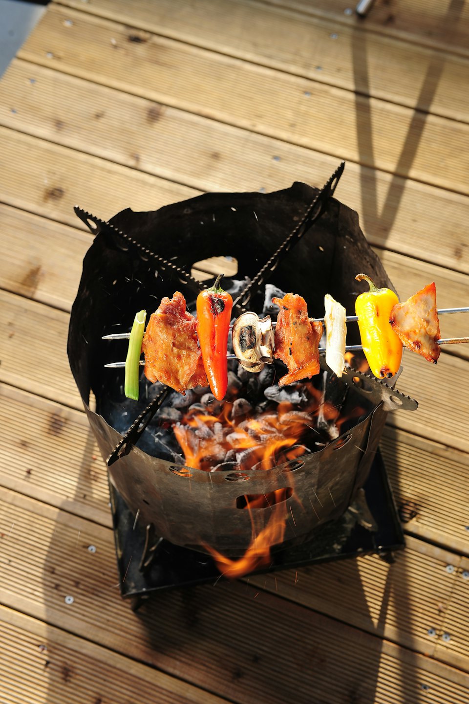 Vardas liha ja köögiviljad grillil kuumade süte kohal terrassil.